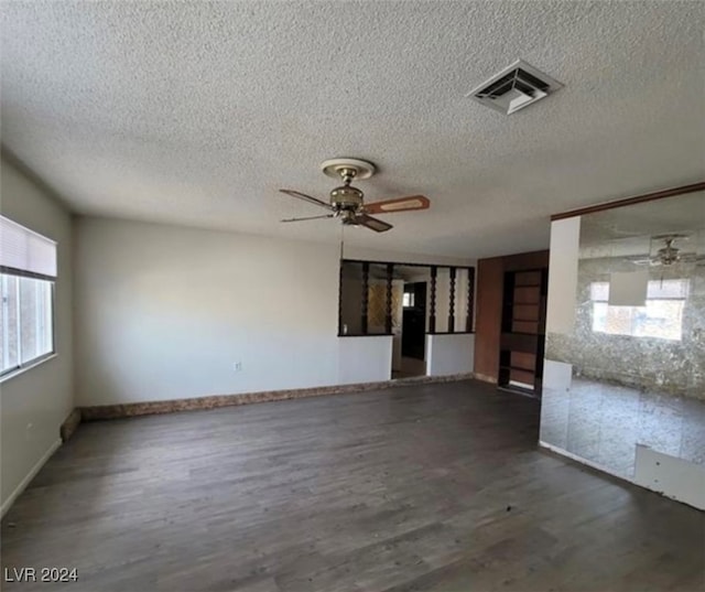 unfurnished room with ceiling fan, dark wood-type flooring, and a textured ceiling