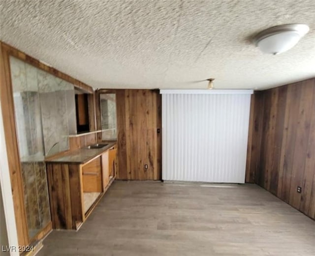 interior space featuring wood-type flooring, wooden walls, and a textured ceiling