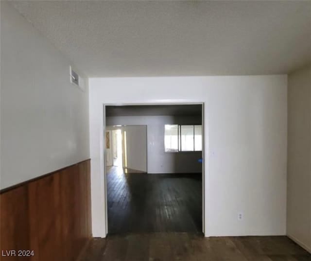 hall with a textured ceiling and dark hardwood / wood-style floors