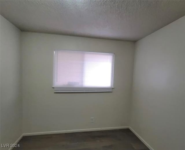 spare room featuring dark hardwood / wood-style floors and a textured ceiling