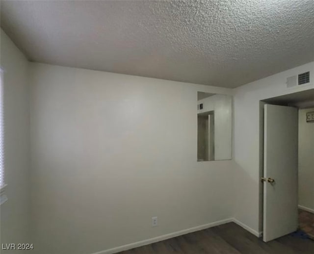 empty room with a textured ceiling and dark hardwood / wood-style flooring