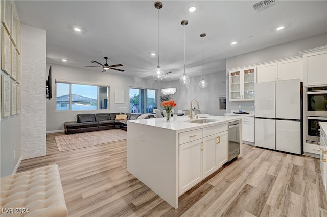 kitchen featuring sink, white cabinetry, light hardwood / wood-style flooring, appliances with stainless steel finishes, and a center island with sink