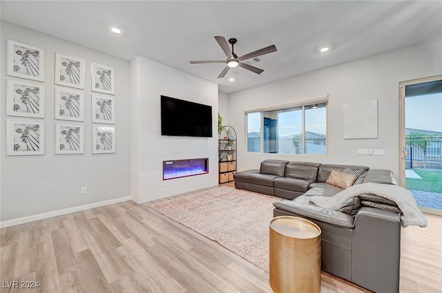 living room featuring a fireplace, light hardwood / wood-style flooring, and ceiling fan