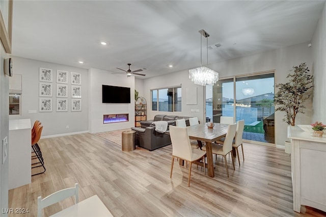 dining room with ceiling fan with notable chandelier and light hardwood / wood-style flooring