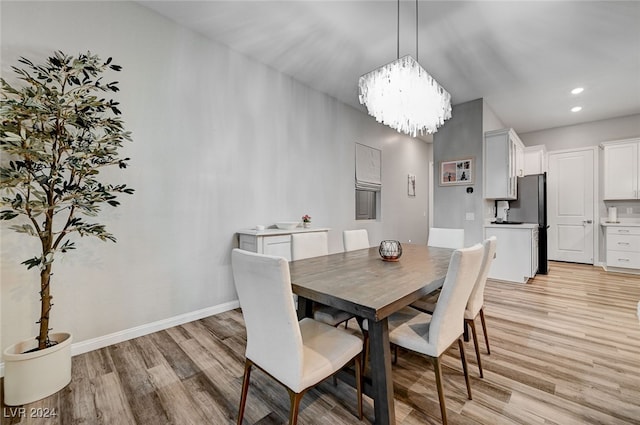 dining area with light wood-type flooring and a chandelier