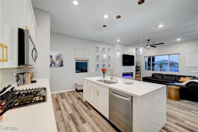 kitchen with a kitchen island with sink, decorative light fixtures, sink, stainless steel appliances, and white cabinetry