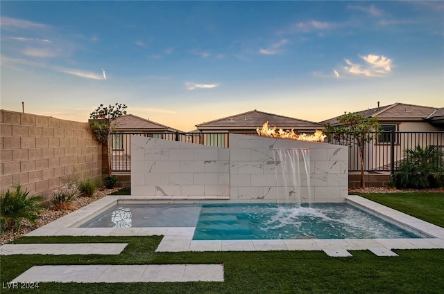 pool at dusk with a lawn and pool water feature