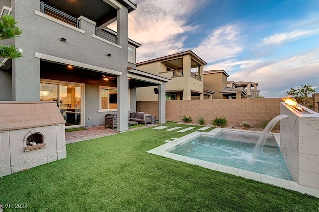 back of house with a jacuzzi, a lawn, a patio, and pool water feature