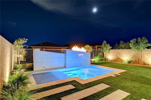 pool at night featuring a yard