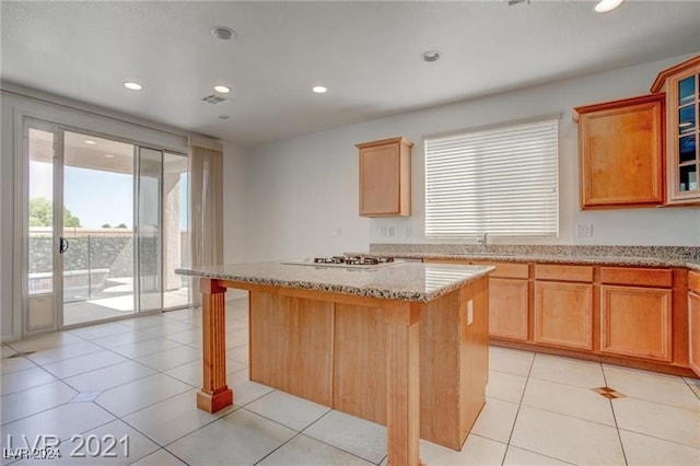 kitchen featuring stainless steel gas cooktop, a kitchen island, a kitchen bar, and light tile patterned floors