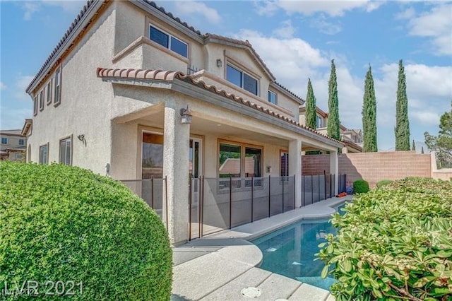 rear view of house featuring a fenced in pool