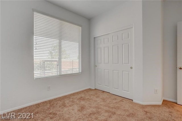 unfurnished bedroom featuring light colored carpet and a closet