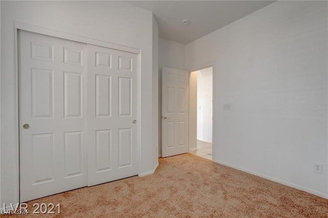 unfurnished bedroom featuring a closet and light colored carpet