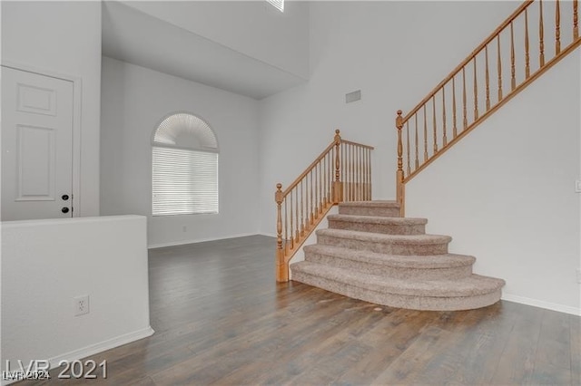 stairs featuring hardwood / wood-style floors and a high ceiling