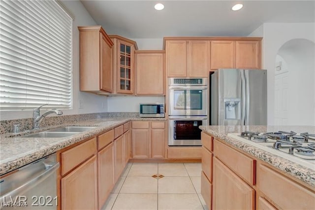 kitchen with appliances with stainless steel finishes, light tile patterned floors, sink, and light brown cabinets