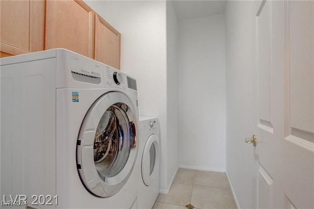 laundry area featuring light tile patterned floors, cabinets, and washer and dryer