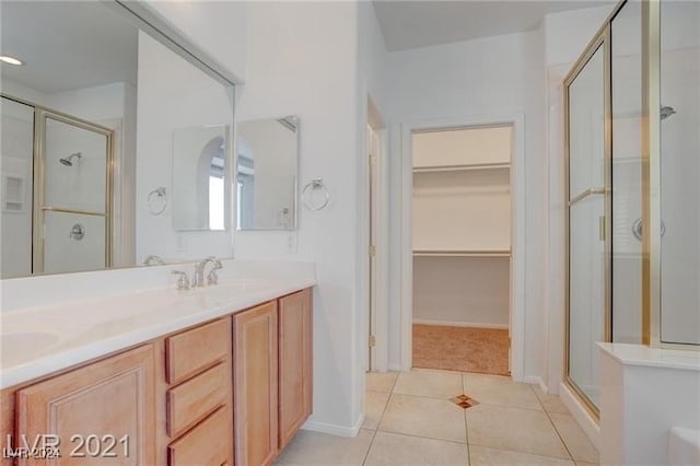 bathroom with tile patterned floors, a shower with door, and vanity