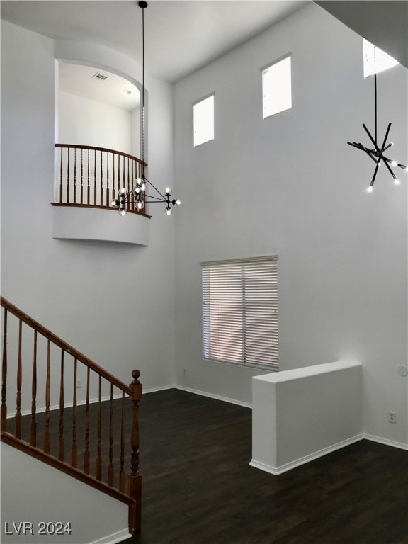 stairs with an inviting chandelier, a high ceiling, and hardwood / wood-style flooring