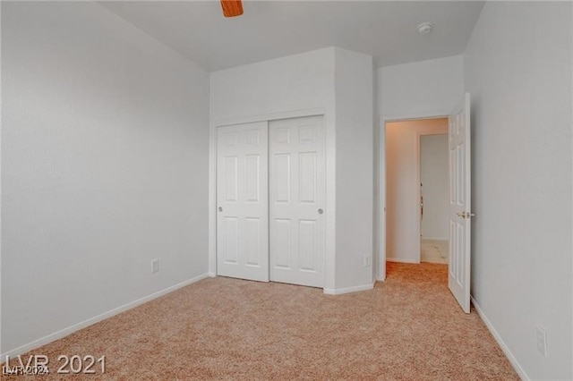 unfurnished bedroom featuring a closet, light colored carpet, and ceiling fan