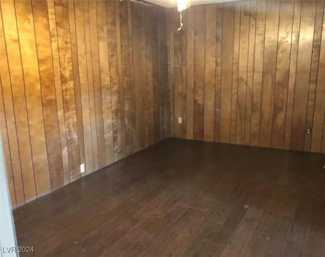 spare room with wooden walls, ceiling fan, and dark hardwood / wood-style flooring