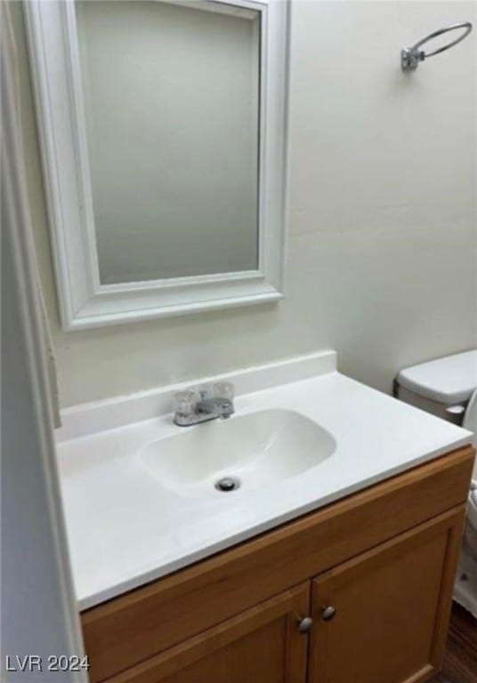 bathroom with hardwood / wood-style floors, vanity, and toilet