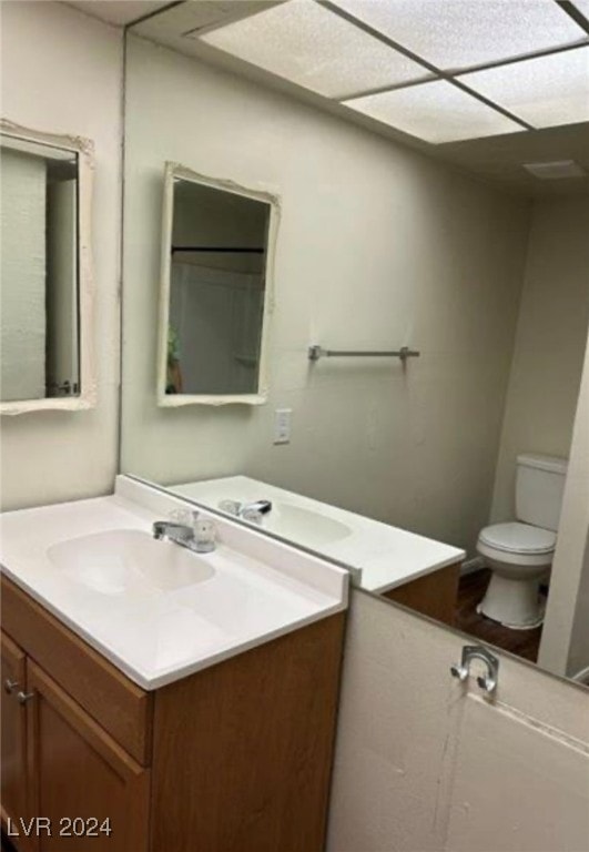 bathroom featuring vanity, a drop ceiling, and toilet