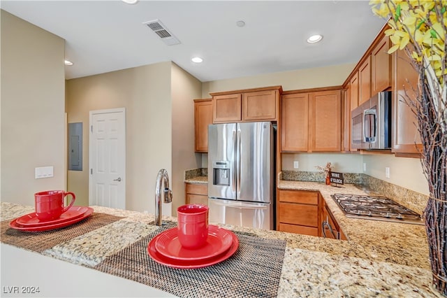 kitchen featuring electric panel, sink, stainless steel appliances, light stone countertops, and kitchen peninsula