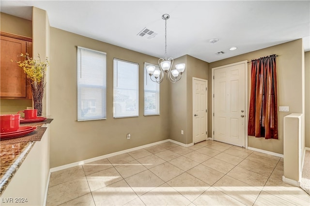 unfurnished dining area with a notable chandelier and light tile patterned floors