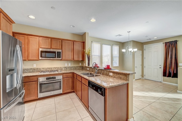 kitchen featuring light stone counters, sink, a chandelier, appliances with stainless steel finishes, and decorative light fixtures