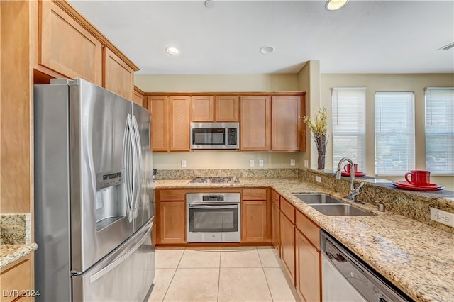 kitchen featuring stainless steel appliances, sink, light tile patterned floors, and light stone counters