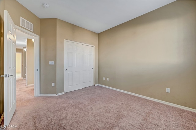 unfurnished bedroom with a closet and light carpet