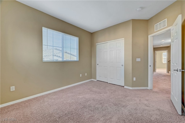 unfurnished bedroom with light carpet and a closet