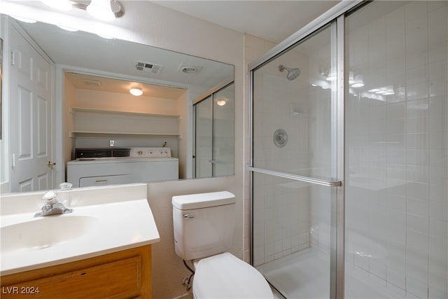 bathroom featuring washer / dryer, vanity, toilet, and a shower with shower door