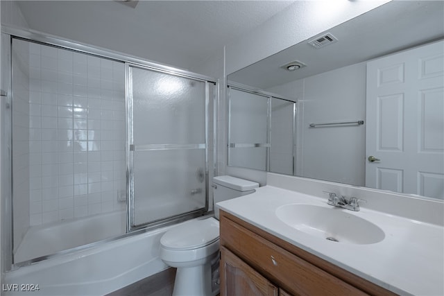 full bathroom with vanity, wood-type flooring, enclosed tub / shower combo, toilet, and a textured ceiling