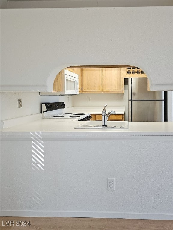 kitchen with wood-type flooring, light brown cabinets, sink, and white appliances