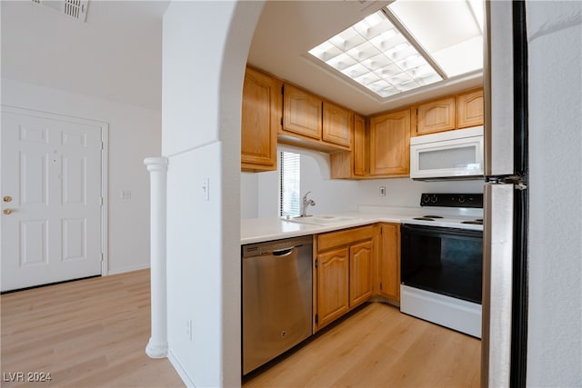 kitchen with light wood-type flooring, sink, and white appliances