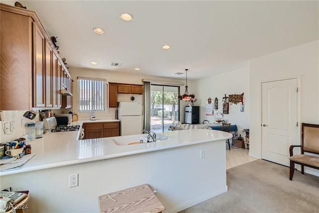 kitchen with white refrigerator, pendant lighting, sink, stainless steel range oven, and kitchen peninsula