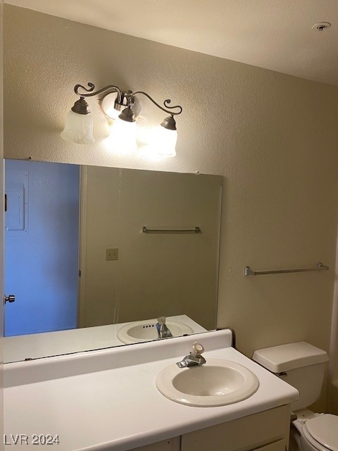 bathroom featuring vanity, toilet, and a textured wall