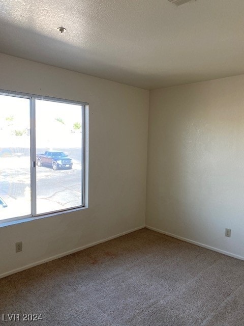 unfurnished room with a textured ceiling, baseboards, and carpet floors