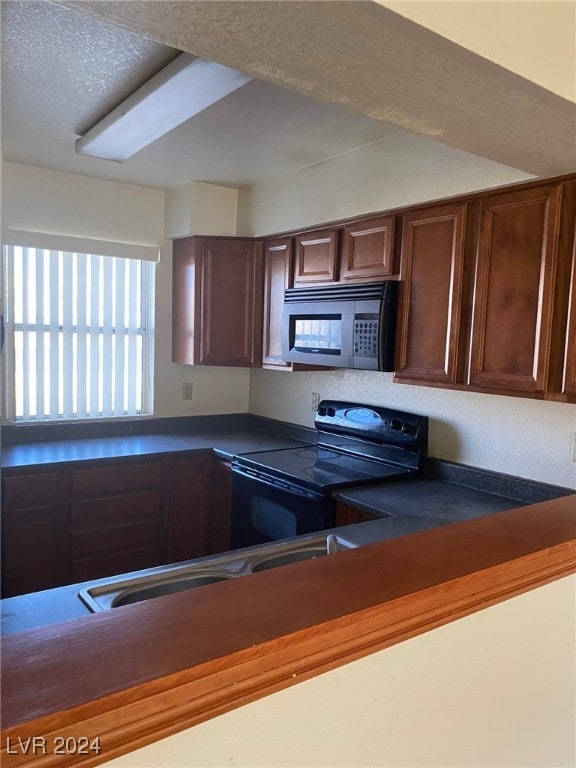 kitchen with dark countertops, black range with electric stovetop, and a textured ceiling