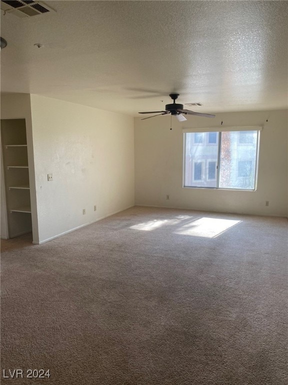 carpeted empty room featuring a textured ceiling and ceiling fan