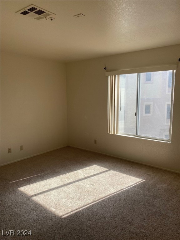 spare room with visible vents, carpet floors, and a textured ceiling