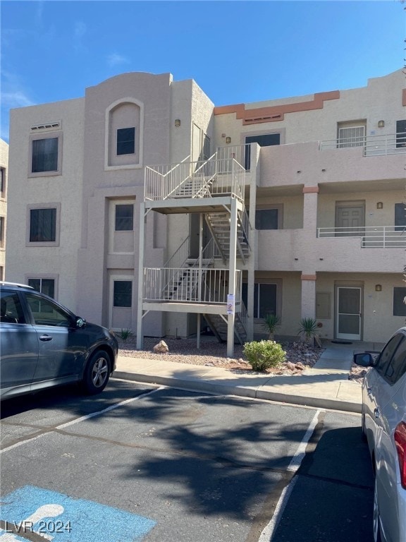 view of building exterior with stairway and uncovered parking