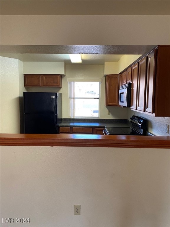 kitchen featuring dark countertops, white microwave, freestanding refrigerator, and range with electric stovetop