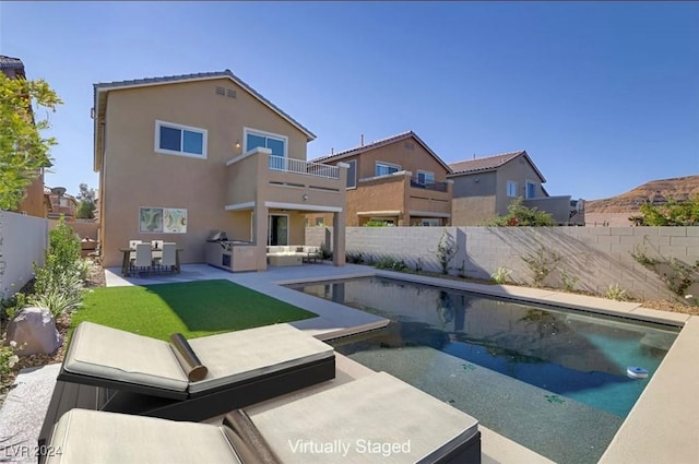 rear view of house with a fenced in pool, a patio area, a balcony, and a lawn