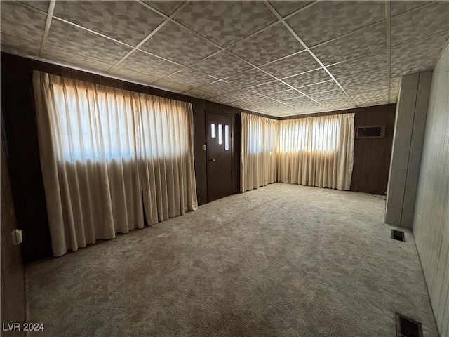 unfurnished room featuring wood walls and carpet flooring