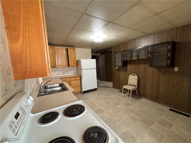 kitchen featuring wood walls, white appliances, and sink