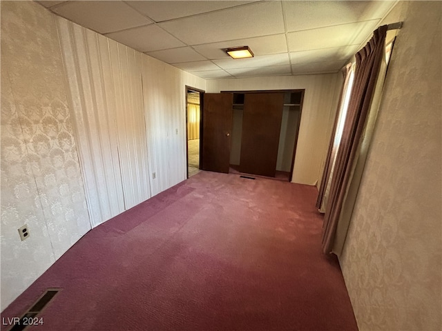 empty room with a drop ceiling and carpet floors