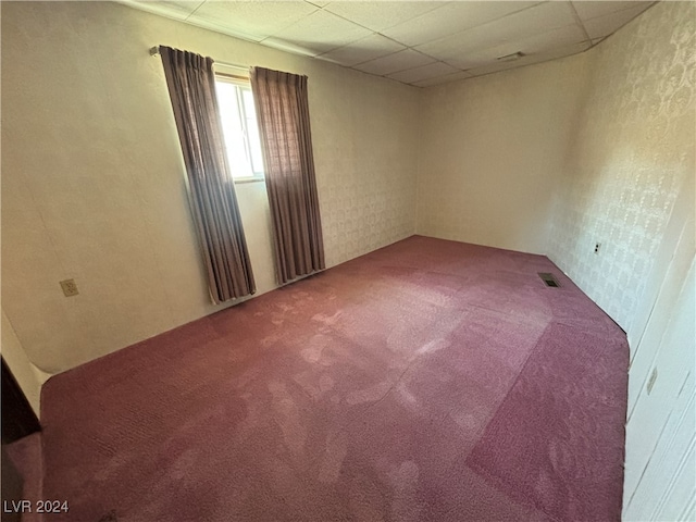 empty room with carpet floors and a paneled ceiling