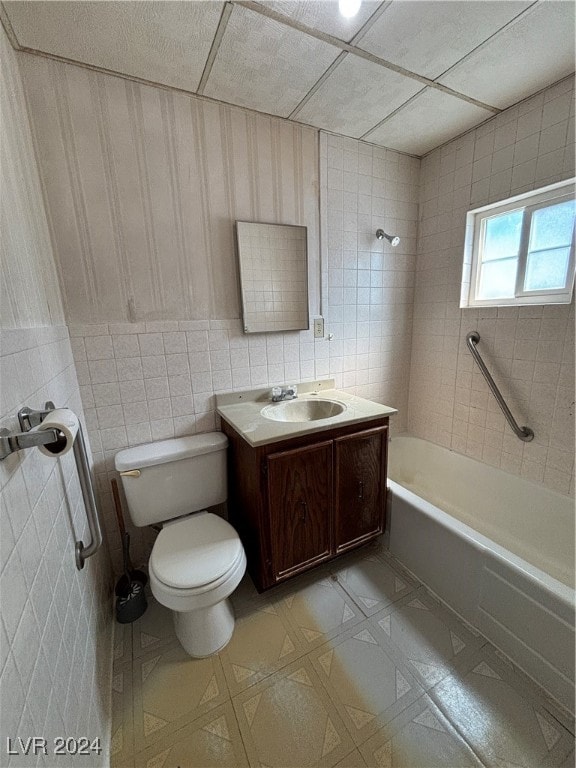 full bathroom with vanity, tile walls, toilet, and tiled shower / bath